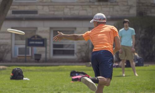 Students playing frisbee on the back quad